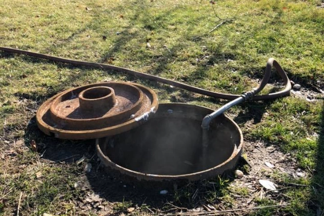 Septic system installation with an open tank and pipes on the ground.
