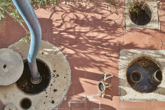 Technician inspecting cesspool maintenance with a cleaning hose.